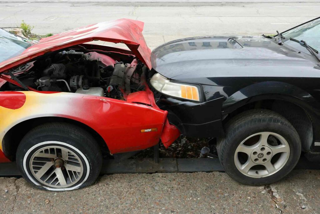 Red car with crumpled hood, rear-ended by black car on street - WebGrit