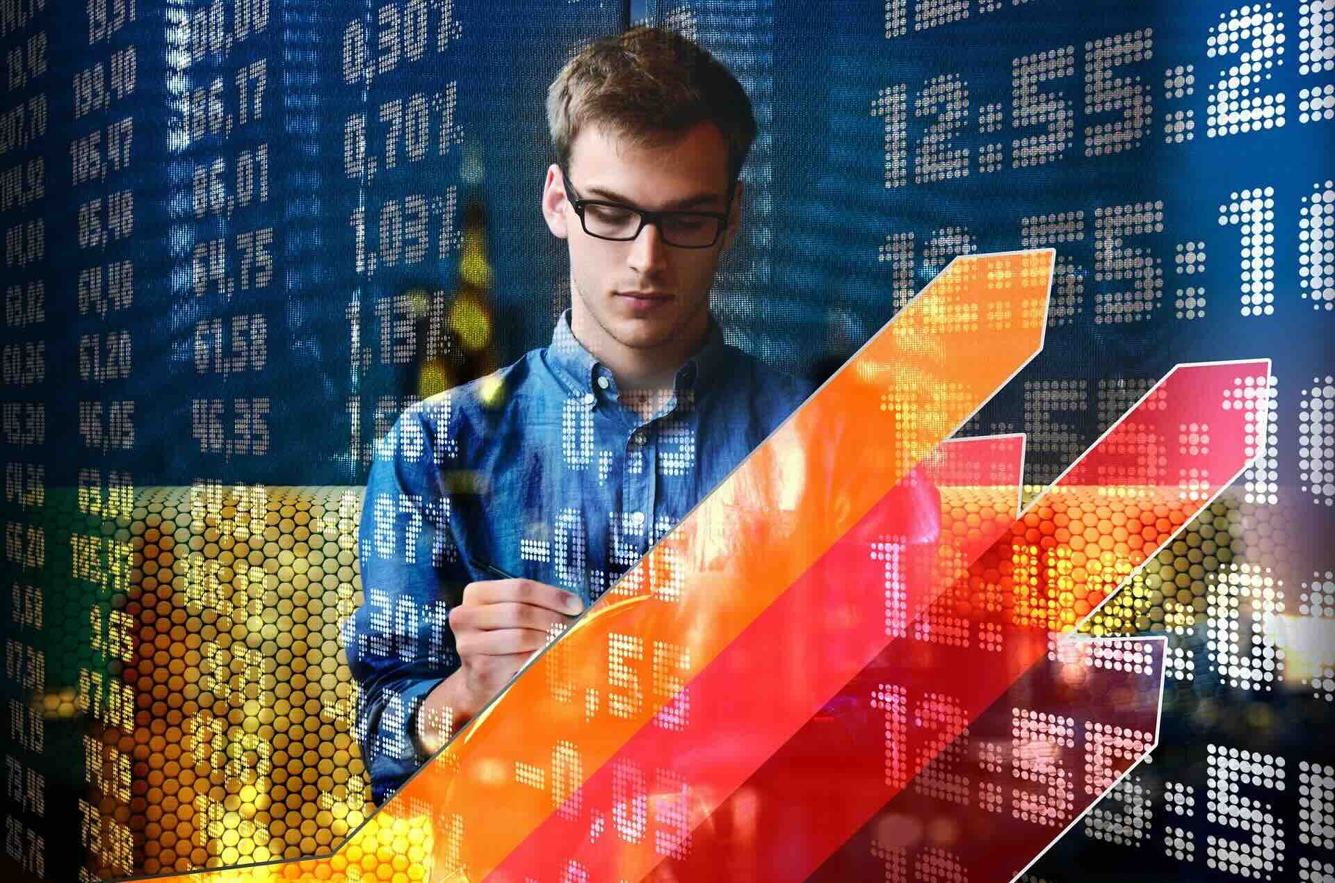 Young Caucasian man wearing glasses and blue shirt, standing in front of arrows slanting up and to the right, against background of numbers - WebGrit
