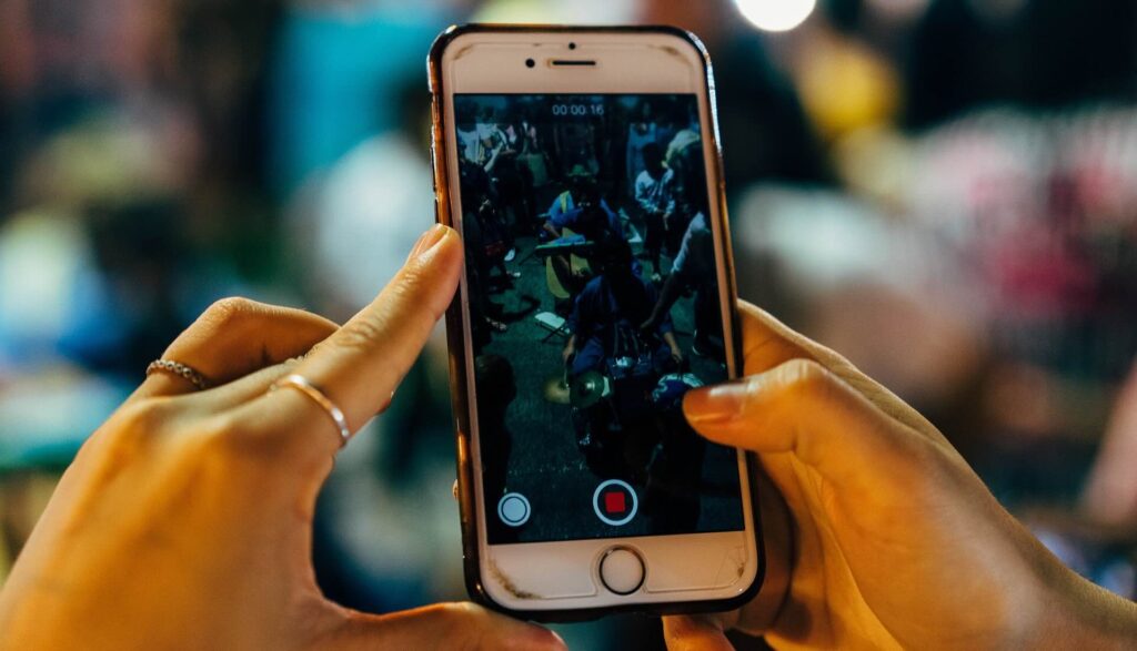 Young woman's hands holding iPhone, recording video - WebGrit